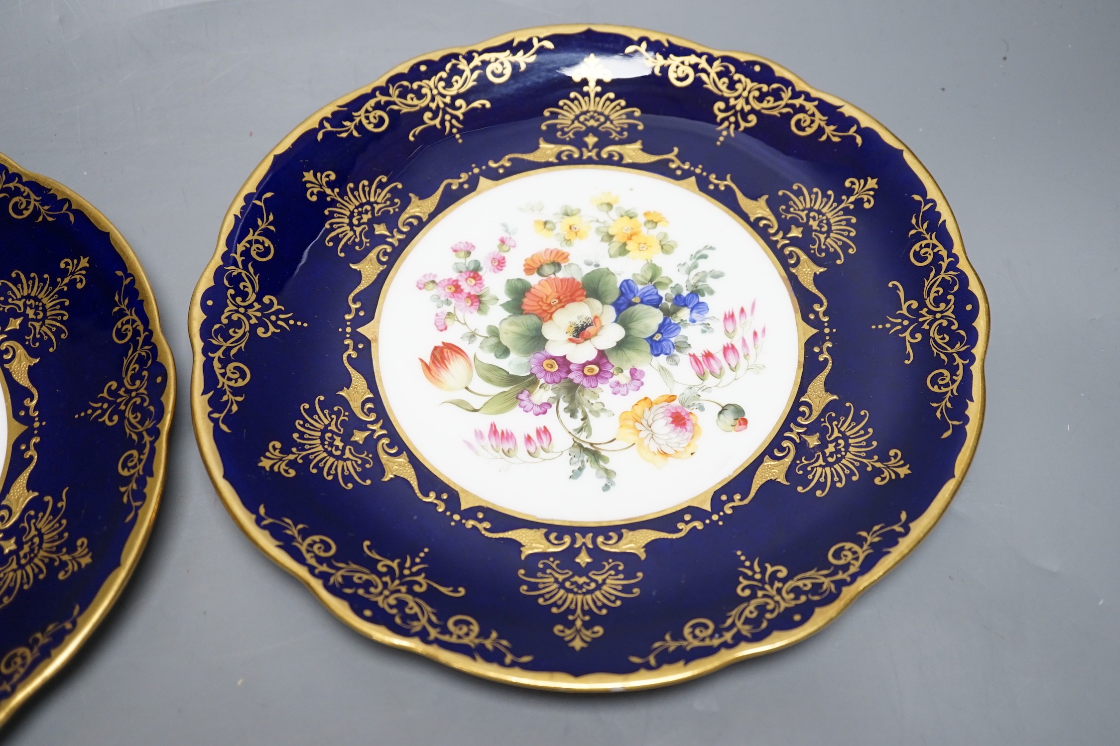 A pair of Coalport floral plates with cobalt blue borders having raised and flat gilding, both by Frank Howard, signed F. Howard, made for Waring and Gillows, Crown England mark